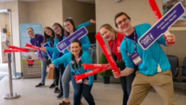 Canada-Wide Science Fair Ambassadors wearing teal and purple, waving signs and welcoming students to CWSF