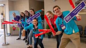 Canada-Wide Science Fair Ambassadors wearing teal and purple, waving signs and welcoming students to CWSF