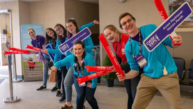 Canada-Wide Science Fair Ambassadors wearing teal and purple, waving signs and welcoming students to CWSF
