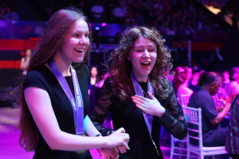 Young girls at Youth Science Canada event celebrating science achievements and innovation with medals and enthusiasm.