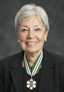 A portrait of Patti Leigh, a dedicated supporter of youth science fairs, wearing a medal and smiling, highlighting her contribution to building science education for youth.