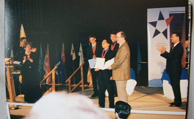 A group of young award winners and judges on stage at Youth Science Canada event, celebrating achievements and the spirit of giving back in science.