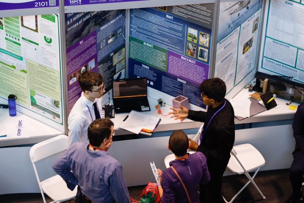 Students and judges discussing a science project at Youth Science Canada event, showcasing student engagement and scientific research.